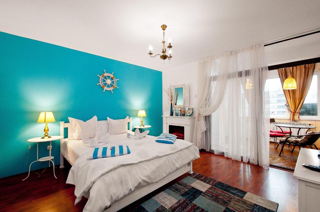 - une chambre avec un grand lit et un mur bleu dans l'établissement Boutique Apartments, à Galaţi