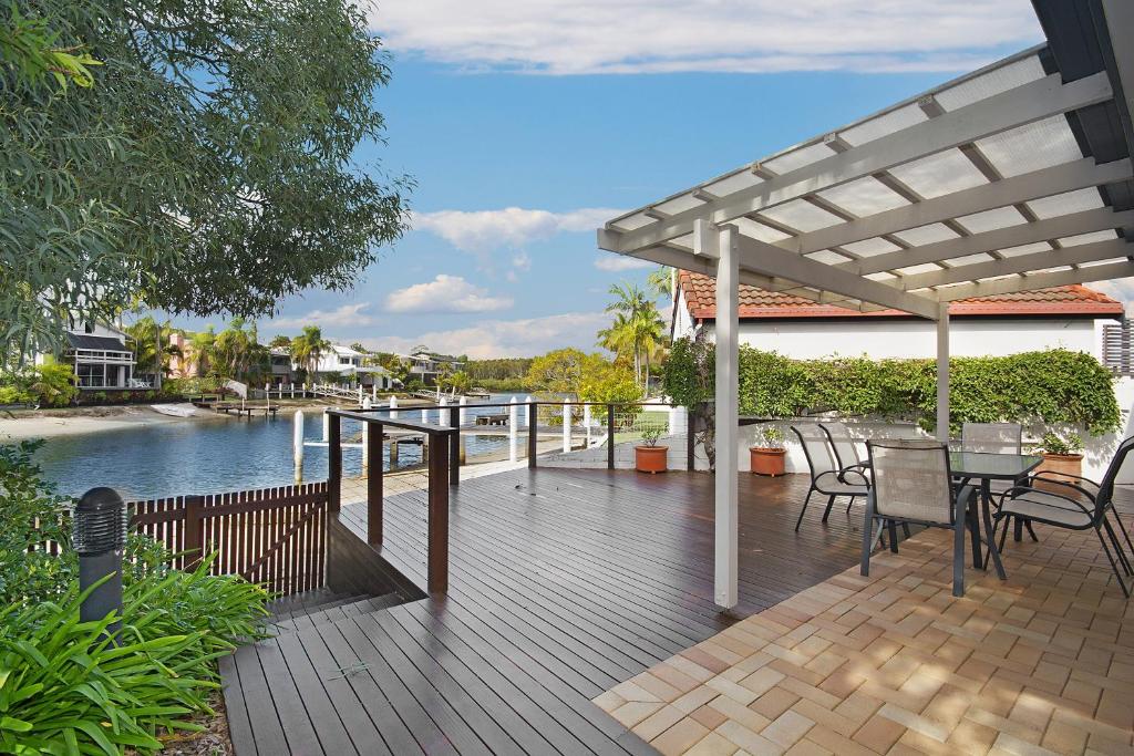 a wooden deck with a table and chairs next to the water at 44 Cooran Court in Noosa Heads