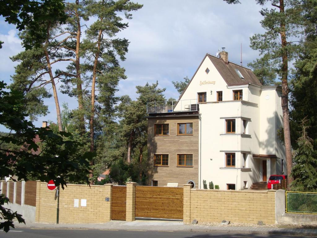 a white house behind a fence at Apartmány FELSENBURG Staré Splavy in Doksy