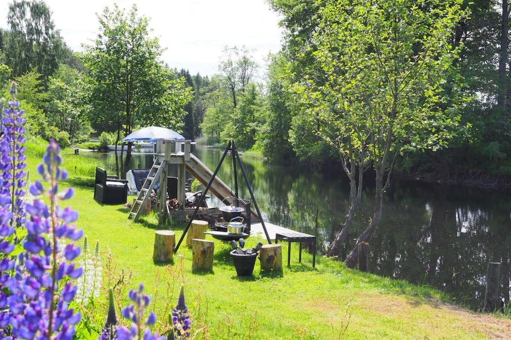 a picnic table with an umbrella next to a river at Riverside Bliss Cozy Apartment near Tvedestrand in Vegårshei