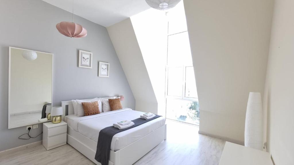 a white bedroom with a bed and a window at Vibrant,affordable Apt 5 Minutes From Metro in Dubai