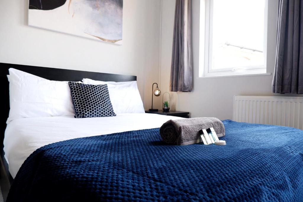 a bedroom with a bed with a blue blanket at COMFORTABLE 4-Bed HOME WITH 3 BATHROOMS AND FREE PARKING! in Cambridge