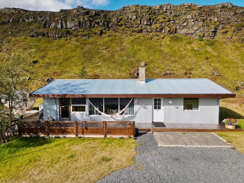 an image of a house with a hill in the background at Kamburinn Cottage in Hveragerði