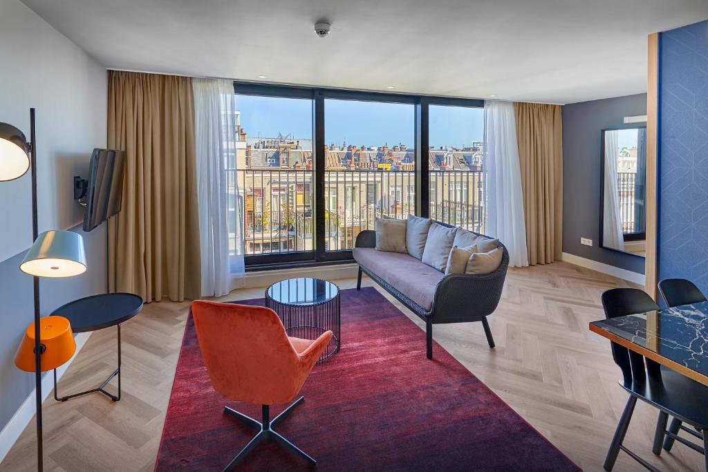 a living room with a couch and a large window at Nova Apartments Amsterdam in Amsterdam