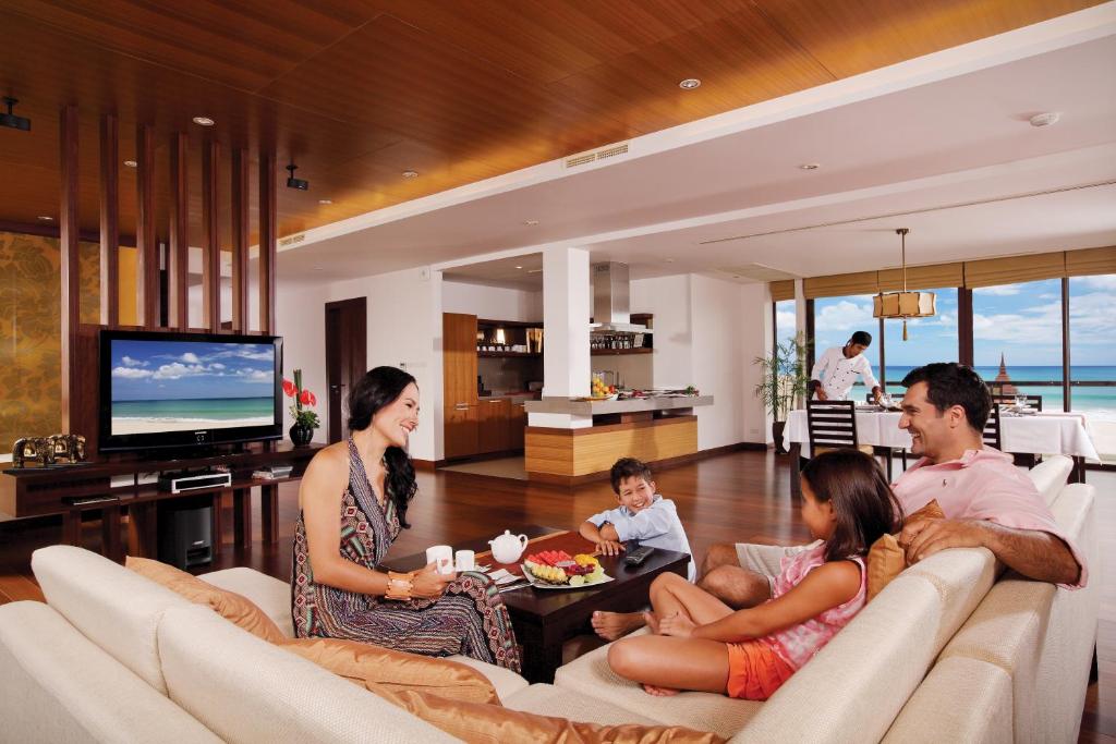 a family sitting on a couch in a living room at Mövenpick Resort Bangtao Beach Phuket in Bang Tao Beach