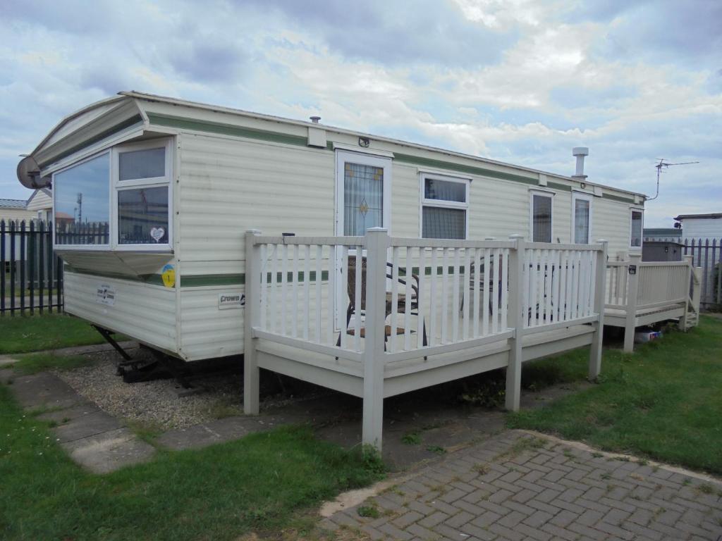 a white caravan with a porch and a fence at Seaview: The Crown:- 6 Berth, Central heated, Enclosed Veranda in Ingoldmells