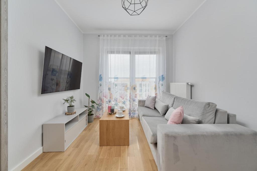 uma sala de estar branca com um sofá e uma televisão em Apartment Jesionowa with FREE GARAGE Wrocław by Renters em Breslávia