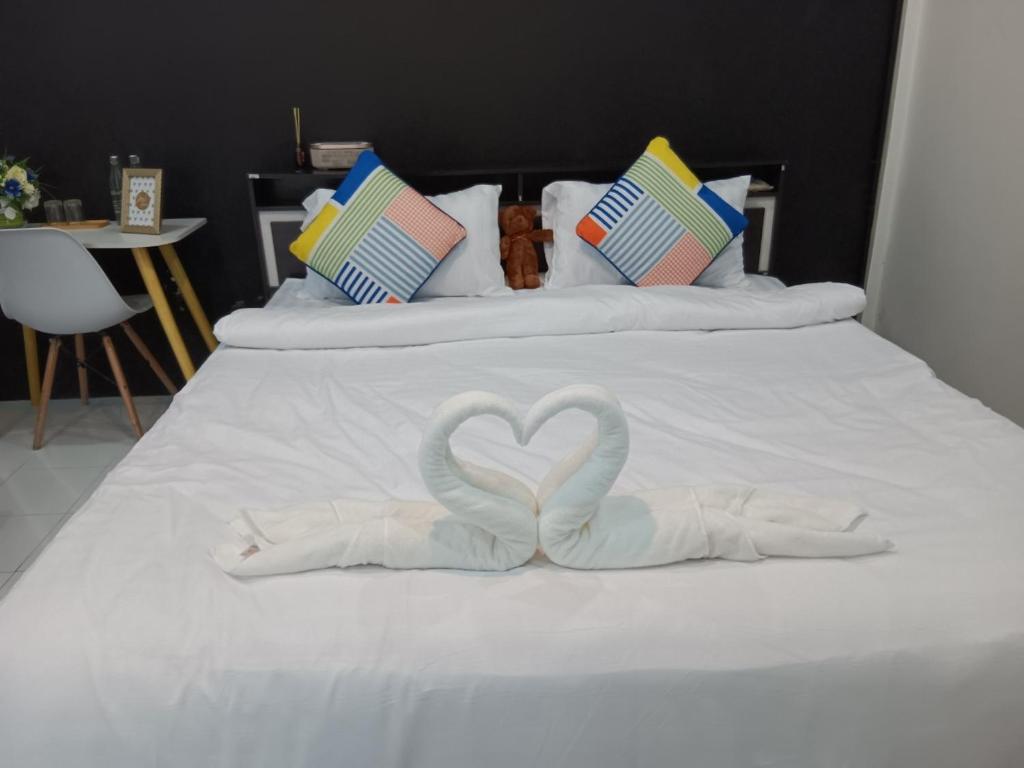 Una cama blanca con dos cisnes formando un corazón en Nimman 9 en Chiang Mai