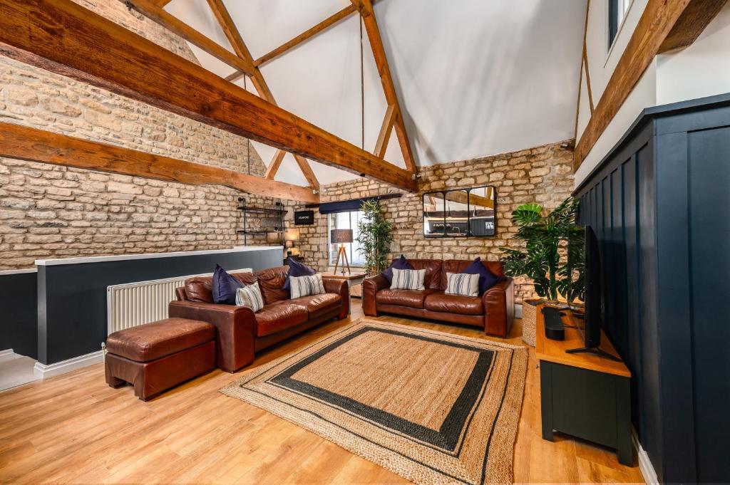 a living room with leather furniture and a brick wall at Luxury town centre loft apartment in converted Granary in Stamford