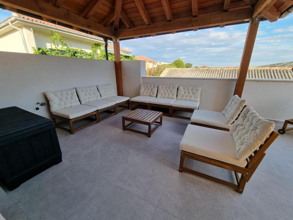 een patio met witte stoelen, een tafel en een tv bij Villa Paro in Pag
