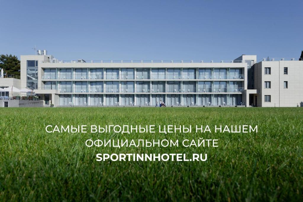 a building in front of a field of green grass at Спорт инн отель и спа in Adler