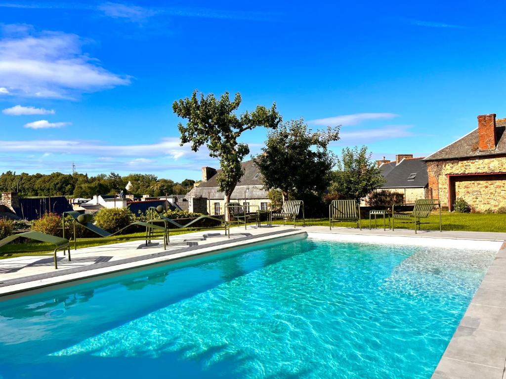 a swimming pool with blue water in front of a house at La Récréation in Châtelaudren