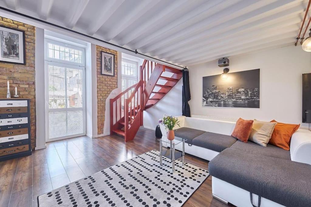 Cozy loft with terrace in the city center في Staré Mesto: غرفة معيشة مع أريكة ودرج