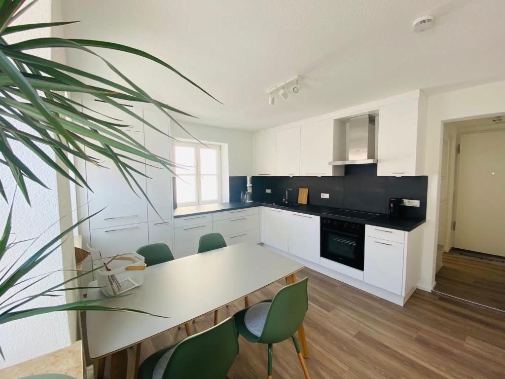 una cocina con mesa y algunas sillas verdes en Trendy Appartement im Zentrum von Nördlingen 50 qm, en Nördlingen