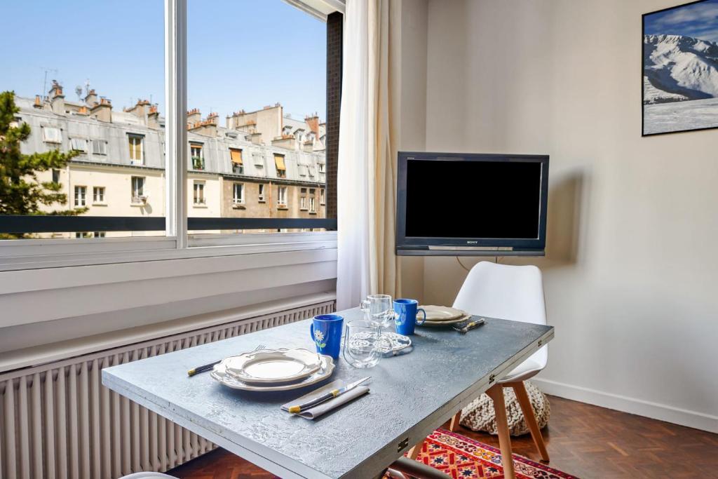 Cette chambre dispose d'une table, d'une télévision et d'une fenêtre. dans l'établissement Appartement Folie-Méricourt - Welkeys, à Paris