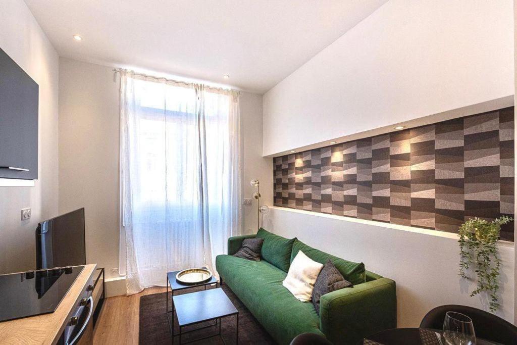 - un salon avec un canapé vert devant une fenêtre dans l'établissement L'horizon, à Saint-Étienne