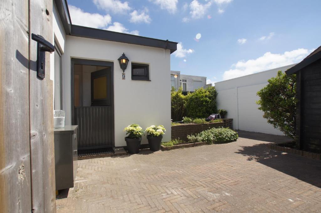 una casa blanca con puerta y macetas en Zomerhuis aan Zee en Zandvoort