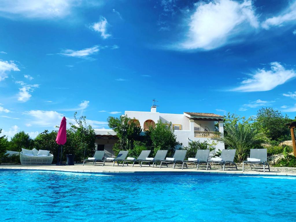 uma piscina com cadeiras e uma casa ao fundo em Villa Can Toni Miquelí em Santa Gertrudis de Fruitera