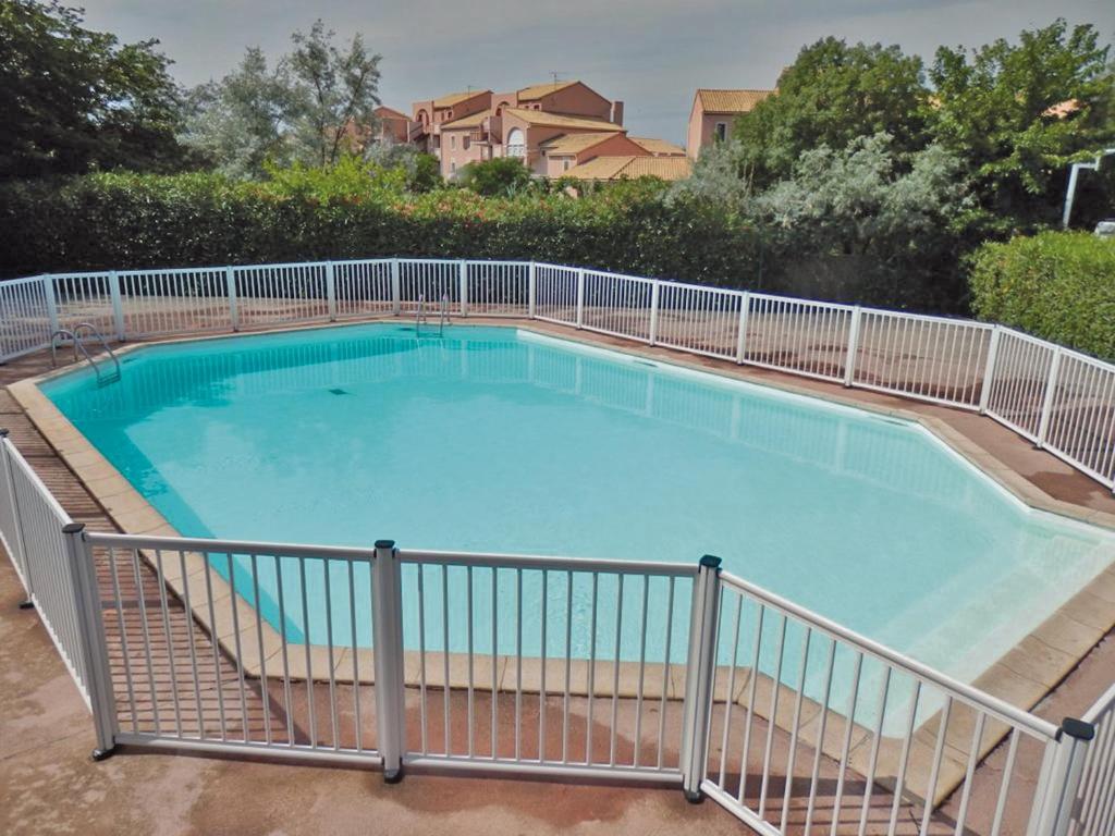 a large swimming pool with a fence around it at Lagrange Vacances Le Scarlett et Les Soleillades in Palavas-les-Flots