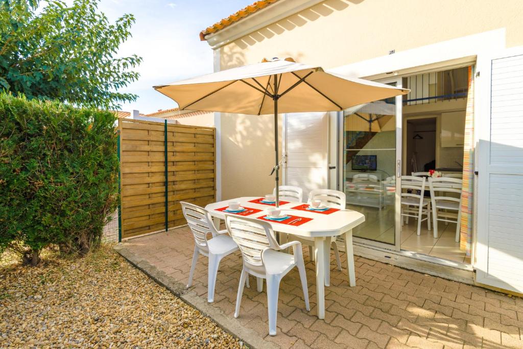 a table and chairs with an umbrella on a patio at Lagrange Vacances Le Scarlett et Les Soleillades in Palavas-les-Flots