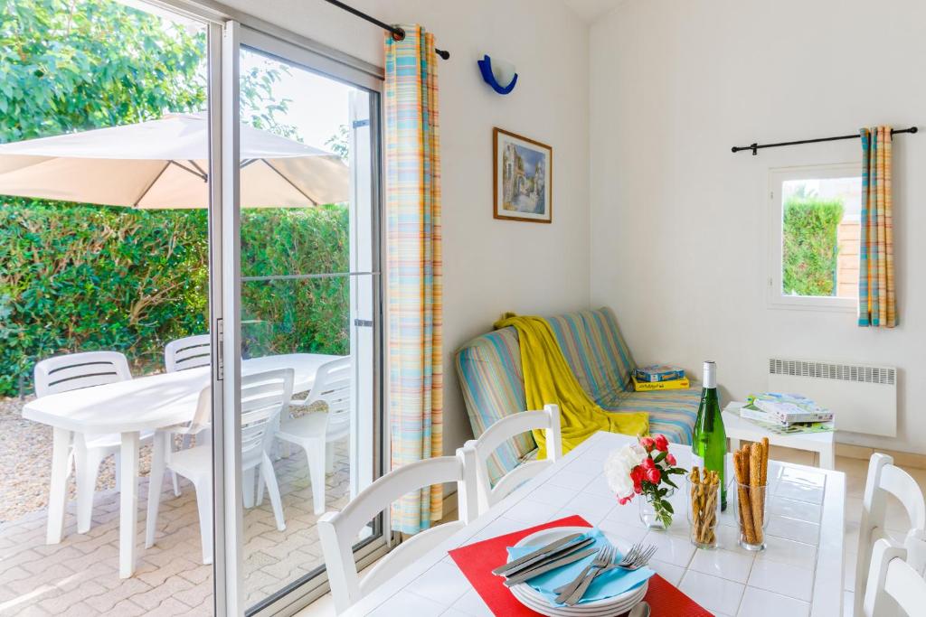 a dining room with a table and chairs and an umbrella at Lagrange Vacances Le Scarlett et Les Soleillades in Palavas-les-Flots