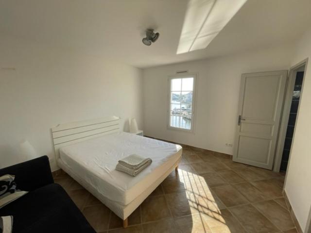 a white bedroom with a bed and a window at Résidence quai St Louis Villa t4 pour 6 personnes N1 47 in Aigues-Mortes