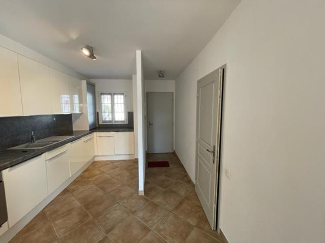a large kitchen with white cabinets and a door at Résidence quai St Louis Villa t4 pour 6 personnes N1 47 in Aigues-Mortes