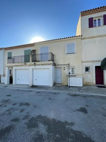 a large house with two garage doors and a balcony at Résidence quai St Louis Villa t4 pour 6 personnes N1 47 in Aigues-Mortes