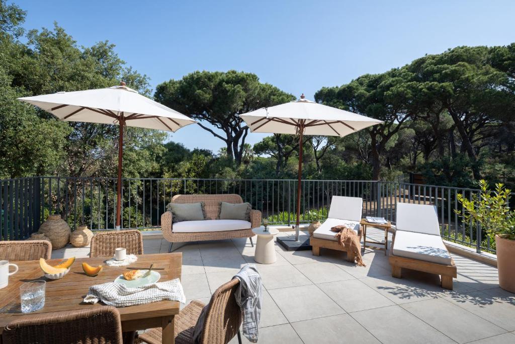 a patio with tables and chairs and umbrellas at Hôtel L'Escalet in Ramatuelle