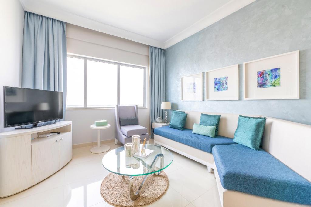 sala de estar con sofá azul y TV en Downtown Luxury - 5 star Hotel Facilities - 5 min walk to Dubai Mall, en Dubái