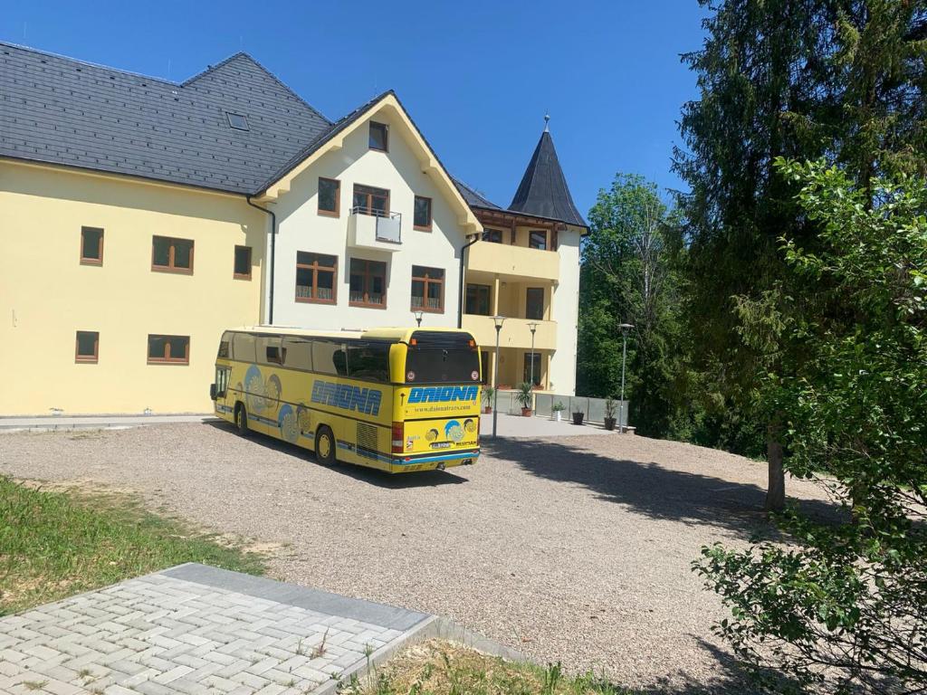 un autobús amarillo estacionado frente a una casa en Penzión Probstner en Nová ľubovňa