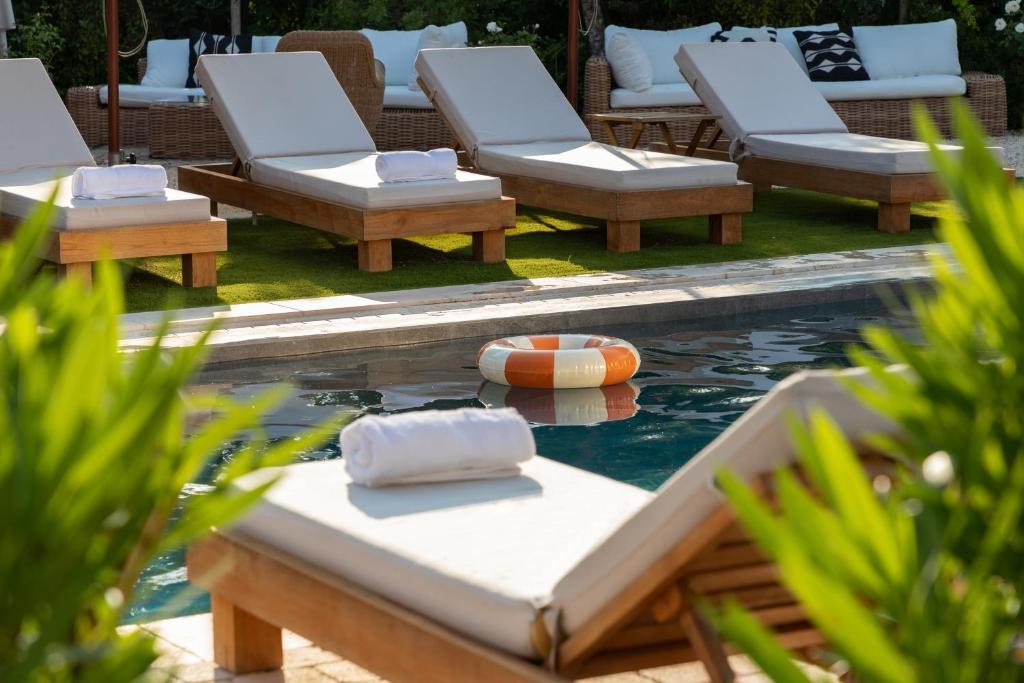 a pool with lounge chairs and a ball in the water at Hôtel L'Escalet in Ramatuelle