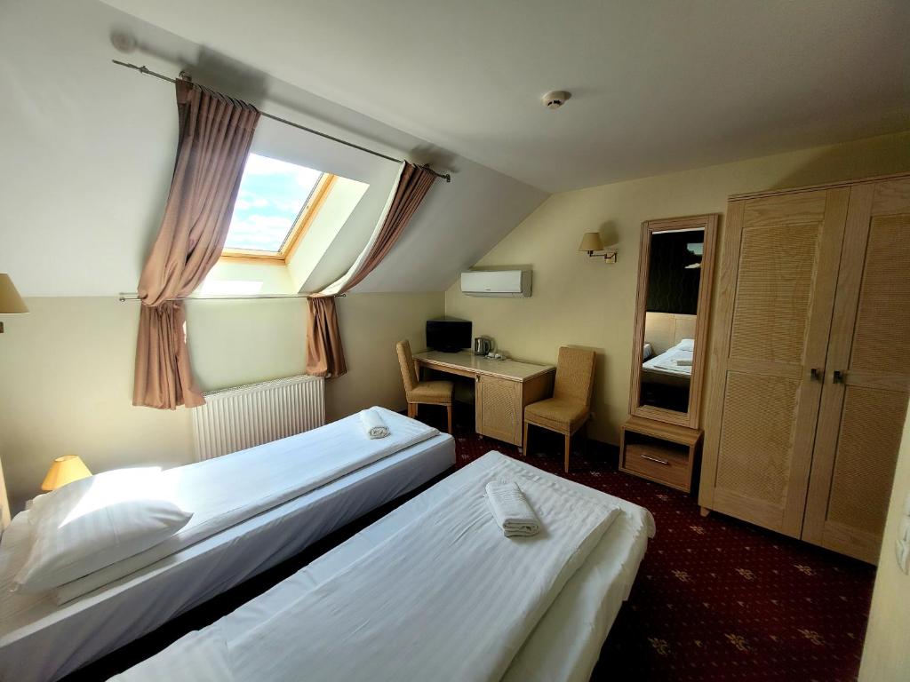 a hotel room with two beds and a desk at Hotel Pajurio vieskelis in Klaipėda