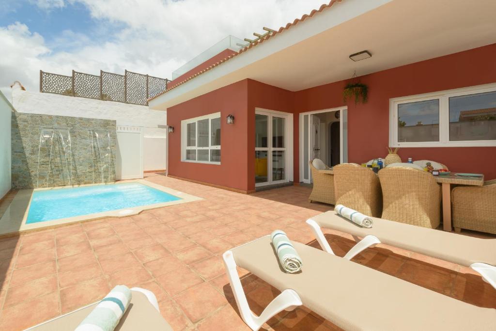 un patio avec des chaises et une piscine dans l'établissement Villa con piscina junto a la playa, à La Estrella