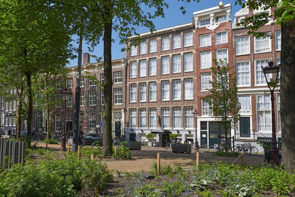 een groot bakstenen gebouw met bomen ervoor bij Nova Hotel in Amsterdam