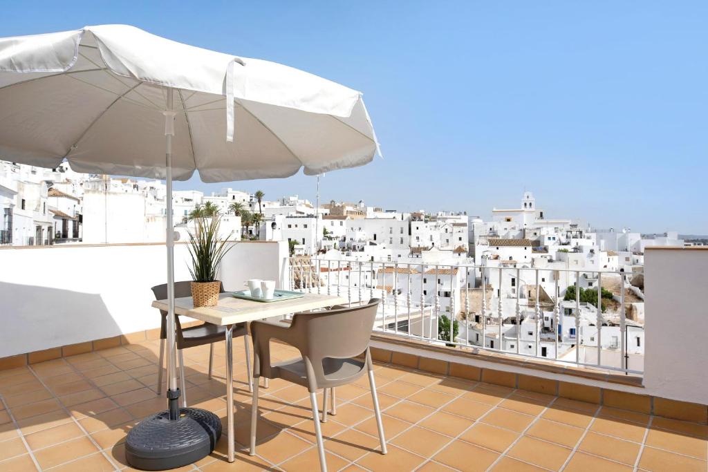 een witte parasol en een tafel en stoelen op een balkon bij Apartamento La Fuente in Vejer de la Frontera