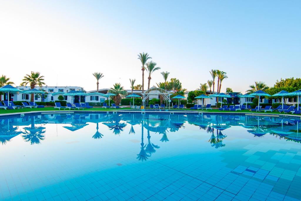 een groot zwembad met palmbomen en huizen bij Ghazala Beach in Sharm El Sheikh