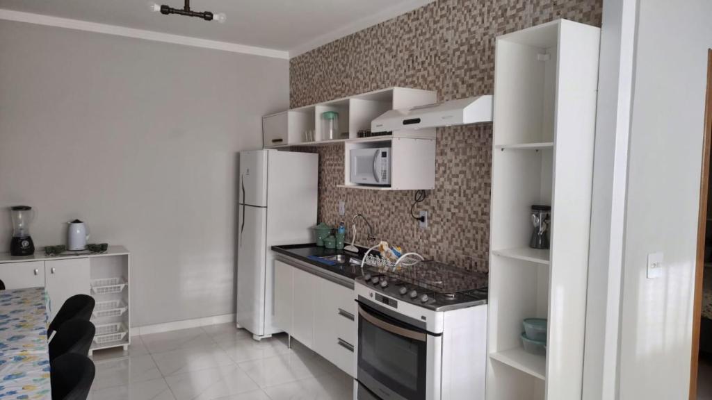 La cuisine est équipée de placards blancs et d'un réfrigérateur blanc. dans l'établissement Wana casa 1 Requinte e conforto, à Sao Jose do Rio Preto