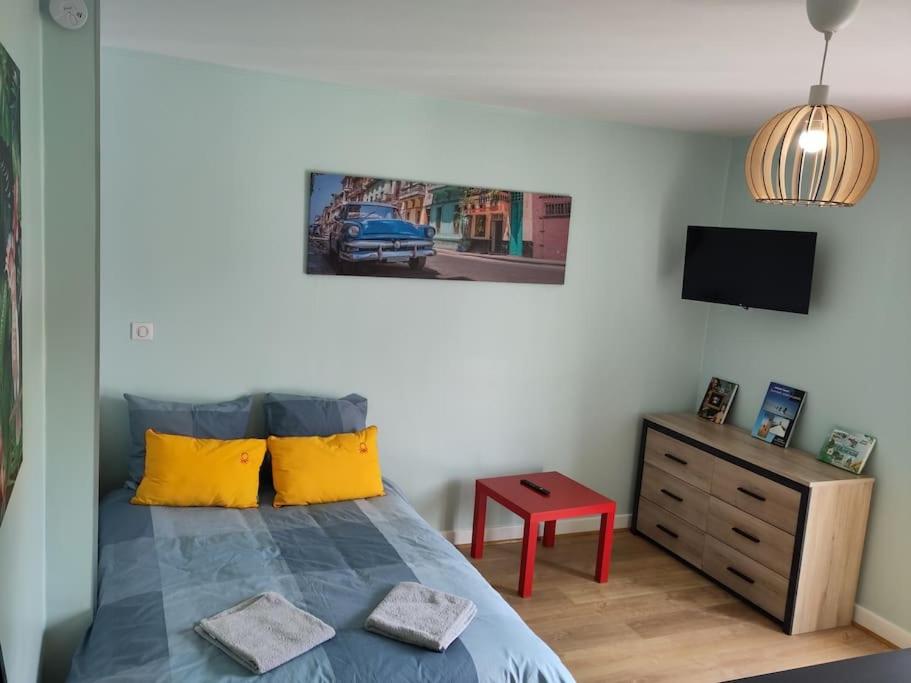 sypialnia z łóżkiem z żółtymi poduszkami i telewizorem w obiekcie appartement refait à neuf pour 3 personnes avec wi-fi w mieście Vic-sur-Cère