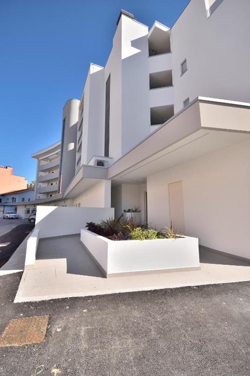 a white building with two white planters in a parking lot at Condominio Aliante in Bibione