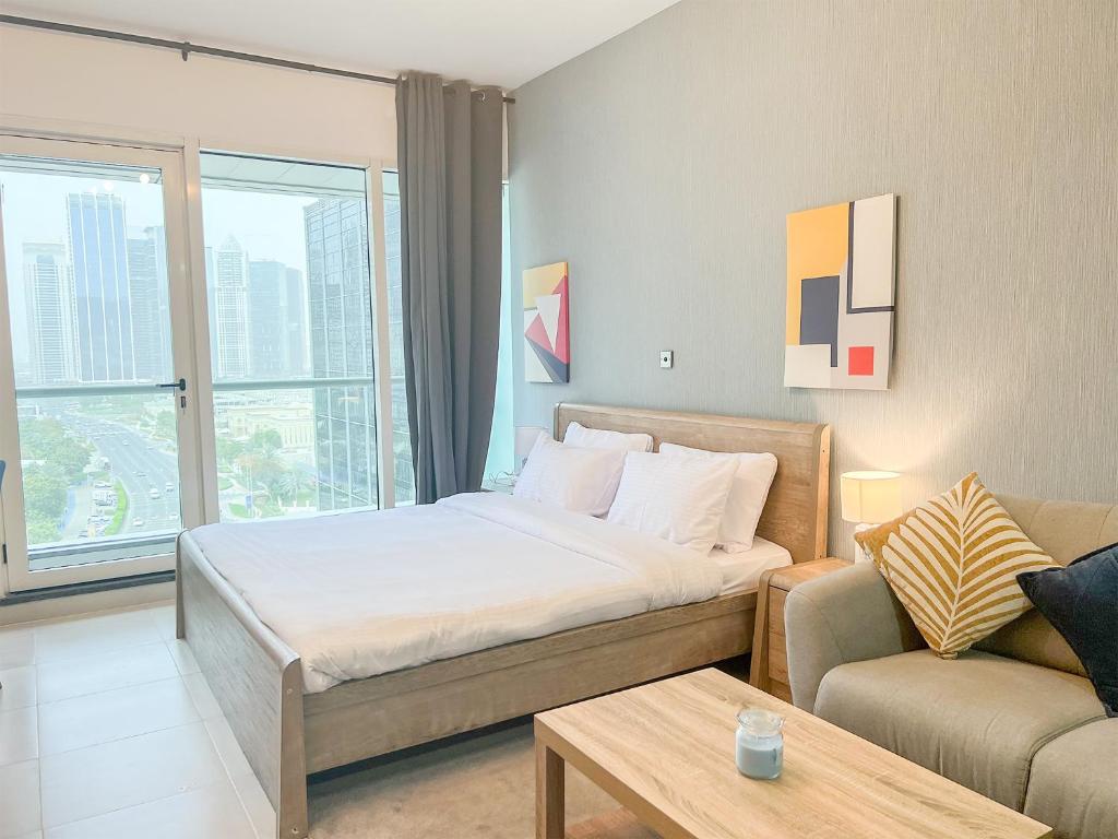 a hotel room with a bed and a couch at Cosmos Living Spacious Studio With Balcony in Dubai