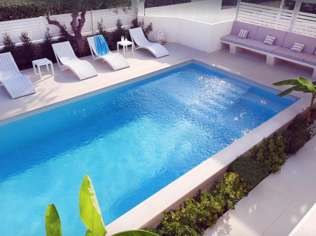 a swimming pool with chairs and a table at Apartment Adriana in Supetar