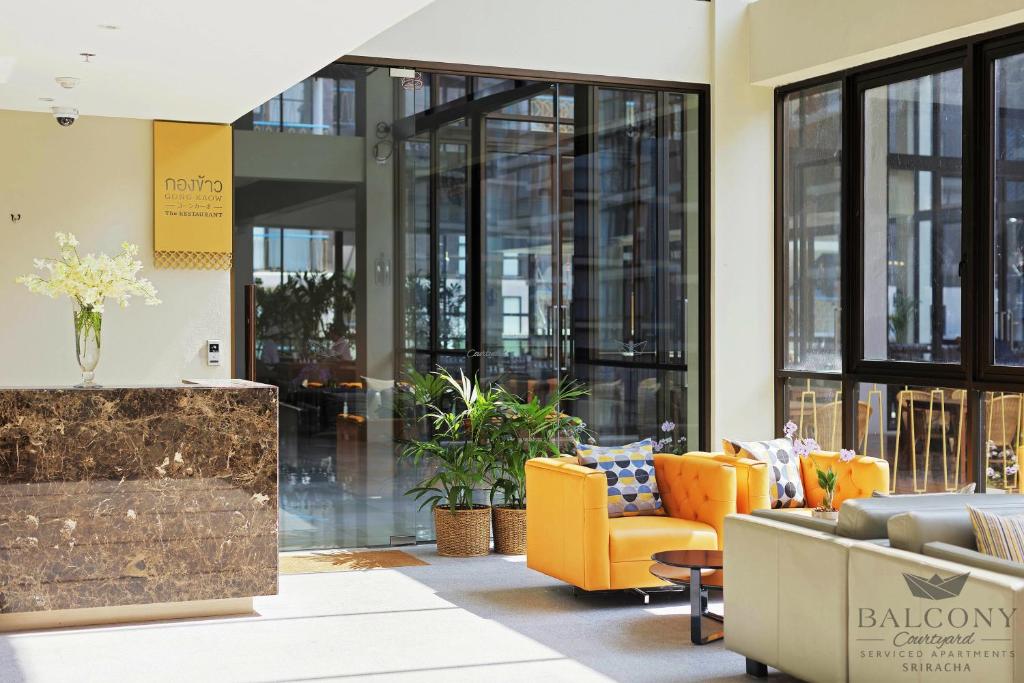 un vestíbulo con muebles y ventanas de color naranja en Balcony Courtyard Sriracha Hotel & Serviced Apartments, en Si Racha