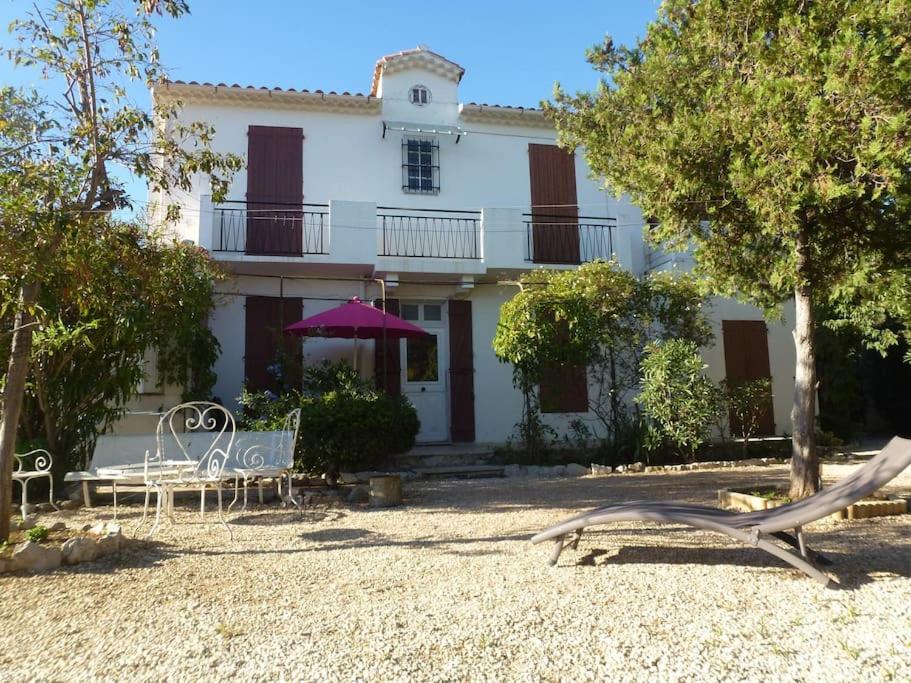 une grande maison blanche avec des chaises et un parasol dans l'établissement La Savinienne de Cassis- 5mn port plage face mer, à Cassis