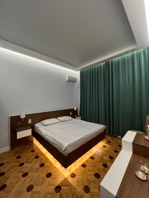 - une chambre avec un lit et un rideau vert dans l'établissement Marco Polo, à Koutaïssi