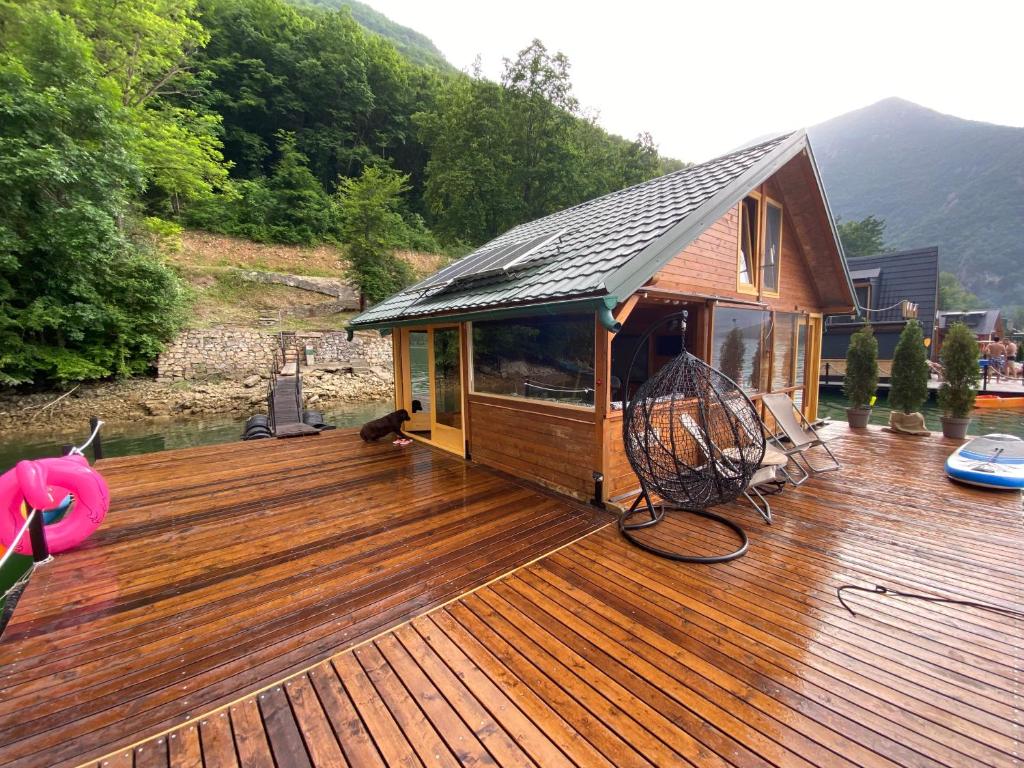 een groot houten terras met een huis op het water bij Viridian Three Boathouse Micah, PERUCAC LAKE in Perućac