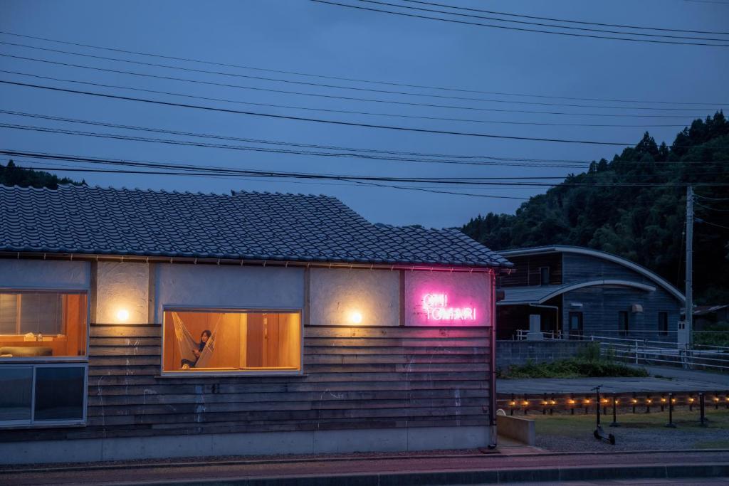 een huis met een neonbord aan de zijkant bij OH!TOMARI in Nanao