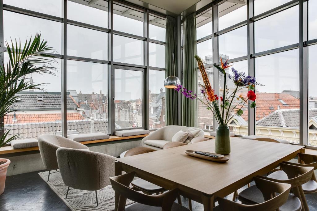una sala da pranzo con tavolo, sedie e finestre di The Duke Boutique Hotel a Den Bosch