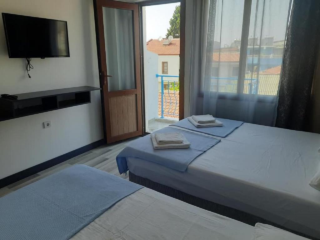 a bedroom with two beds and a television and a window at Ephesian Hotel & Guesthouse in Kusadası