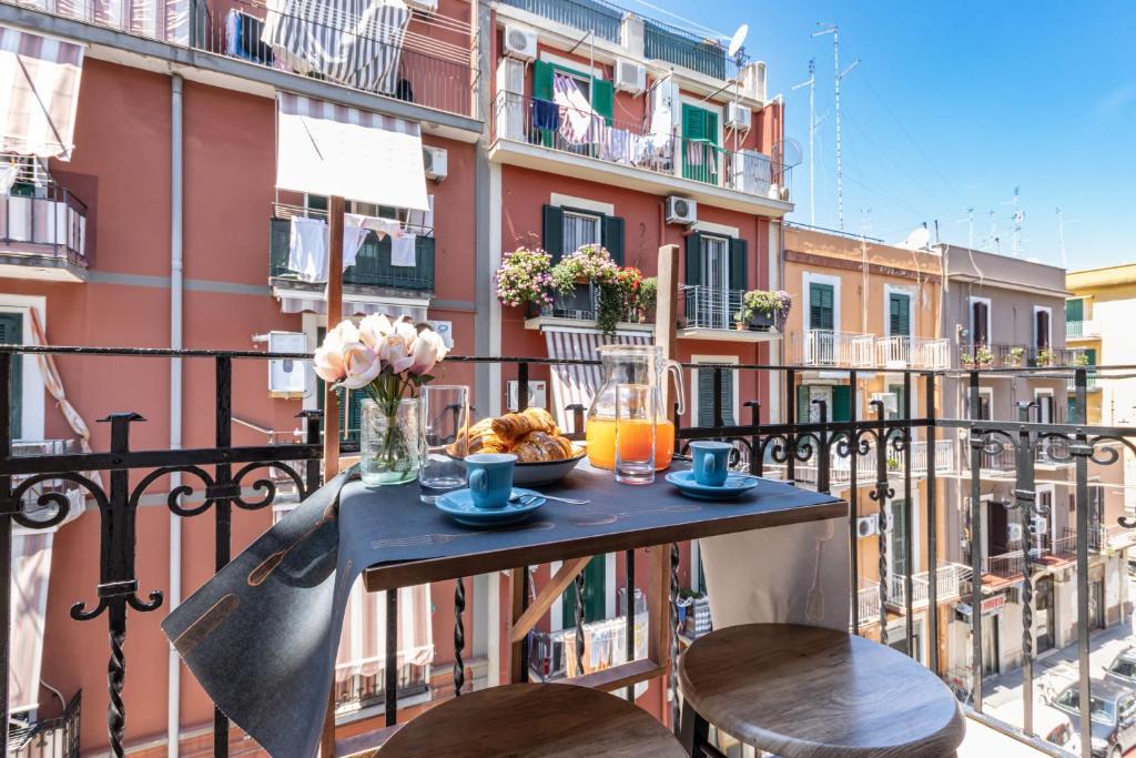 einen Tisch auf dem Balkon mit Speisen und Getränken in der Unterkunft San Nicola Apartments by Rentbeat in Bari